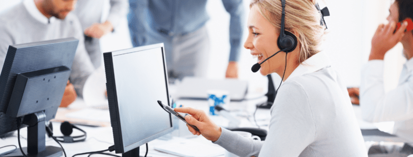 blonde customer service representative sitting in front of computer at her desk providing support